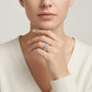 Editorial fashion lookbook portrait of a model styling a timeless romantic round cut moissanite halo bridal ring near her face.