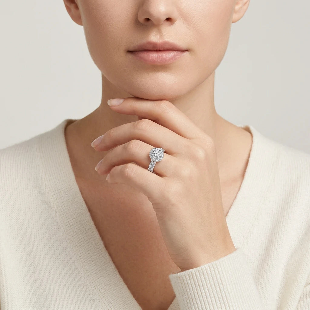 Editorial fashion lookbook portrait of a model styling a timeless romantic round cut moissanite halo bridal ring near her face.