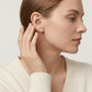 Editorial fashion lookbook portrait of a model styling timeless romantic vca inspired moissanite clover studs with a white top.