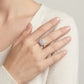 Lifestyle fashion lookbook portrait of a model styling a sugar cube halo cluster moissanite ring across her chest.