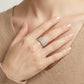 Lifestyle fashion lookbook portrait of a model styling a wide wave pave moissanite crossover ring across her chest.
