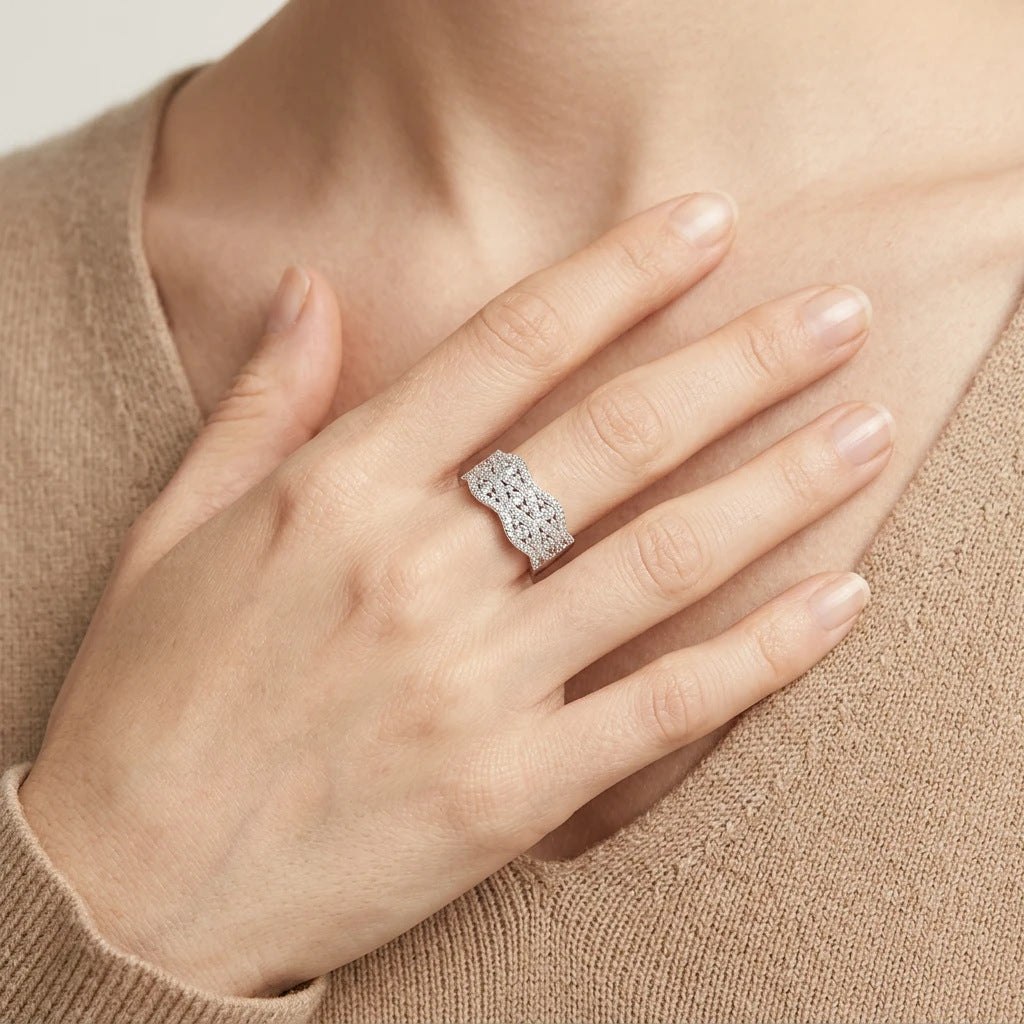 Lifestyle fashion lookbook portrait of a model styling a wide wave pave moissanite crossover ring across her chest.