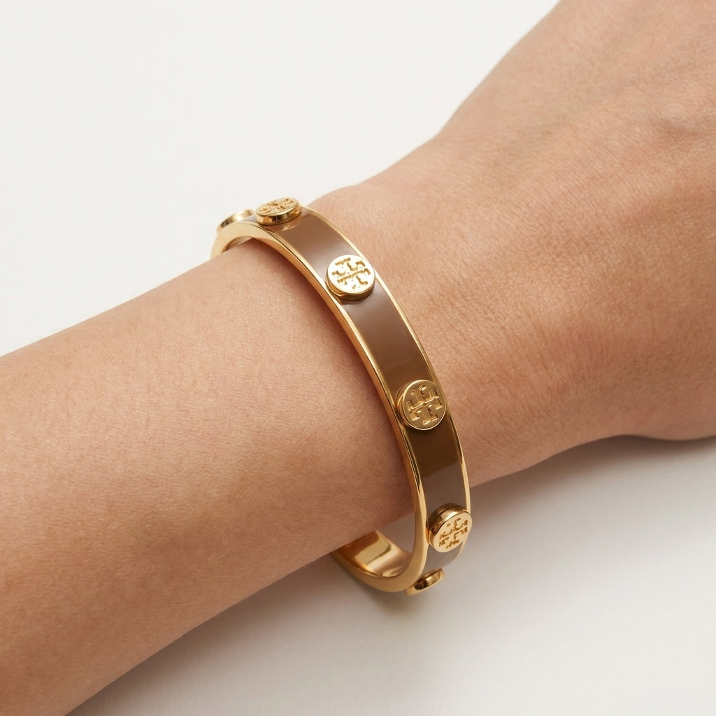 Close-up view of the Tory Burch Two-Tone Bangle showing the comfortable oval shape for wrist fit