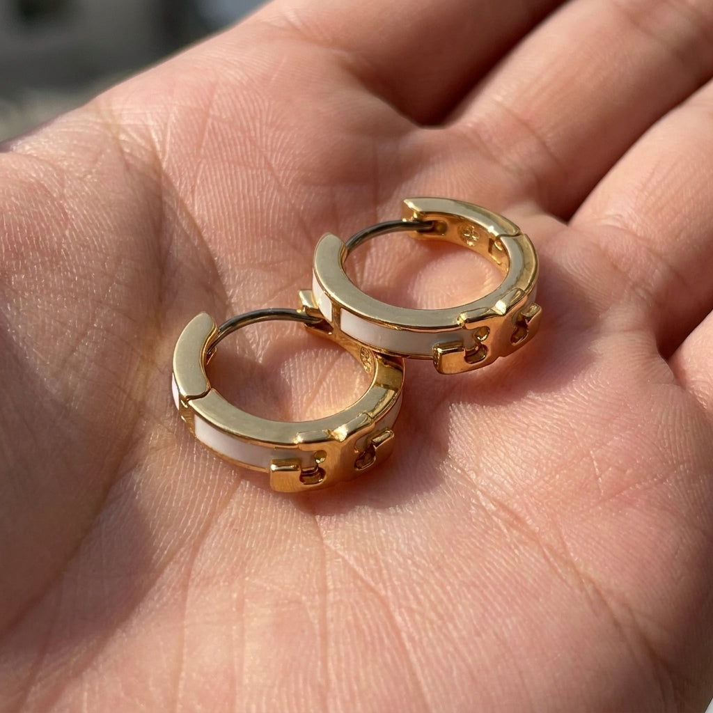 Hand-held size reference of Tory Burch Kira Enamel Huggies to show the petite 12mm hoop scale