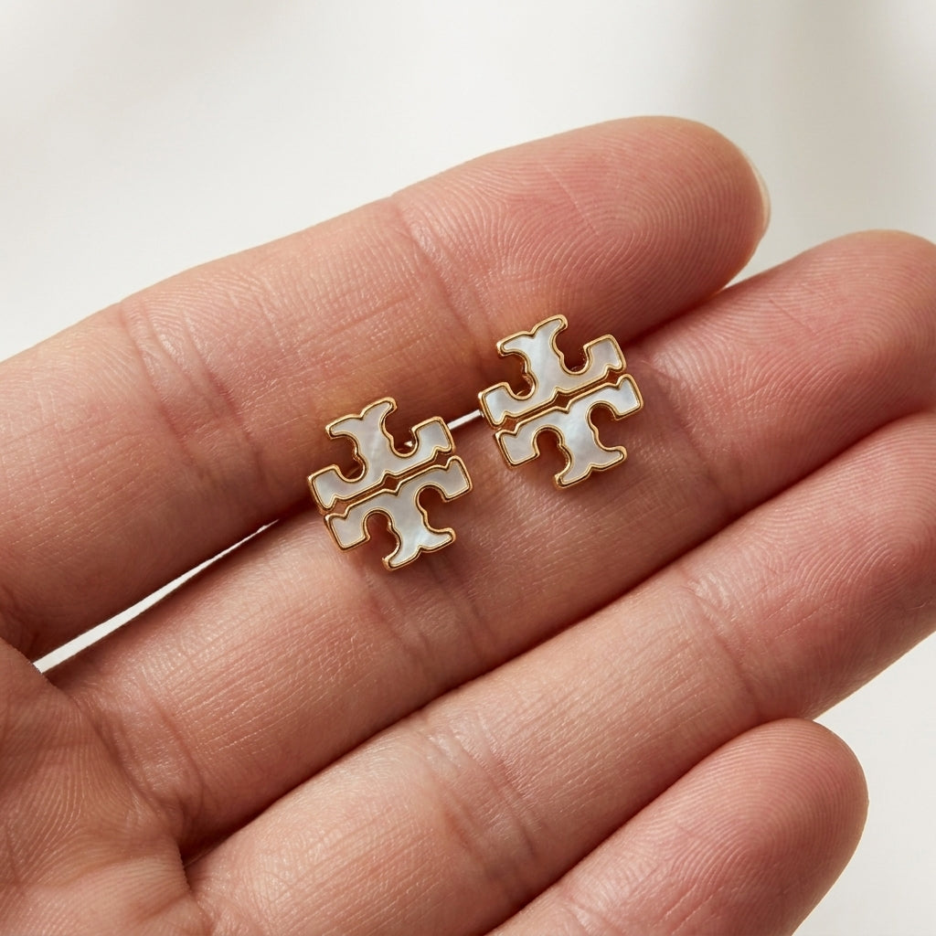 Hand-held size reference of Tory Burch Small Enamel Studs to show the petite scale for daily wear