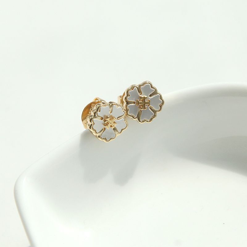 Side view of the Tory Burch Forget Me Not floral stud earrings showing the intricate white enamel petals and gold-tone finish.