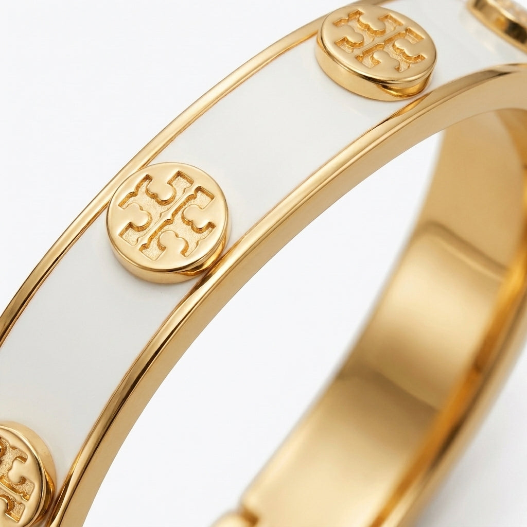 Macro detail of the polished gold edges and smooth white enamel finish on the Tory Burch cuff
