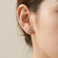 Close-up of a model wearing Tory Burch gold stud earrings, showcasing everyday elegance