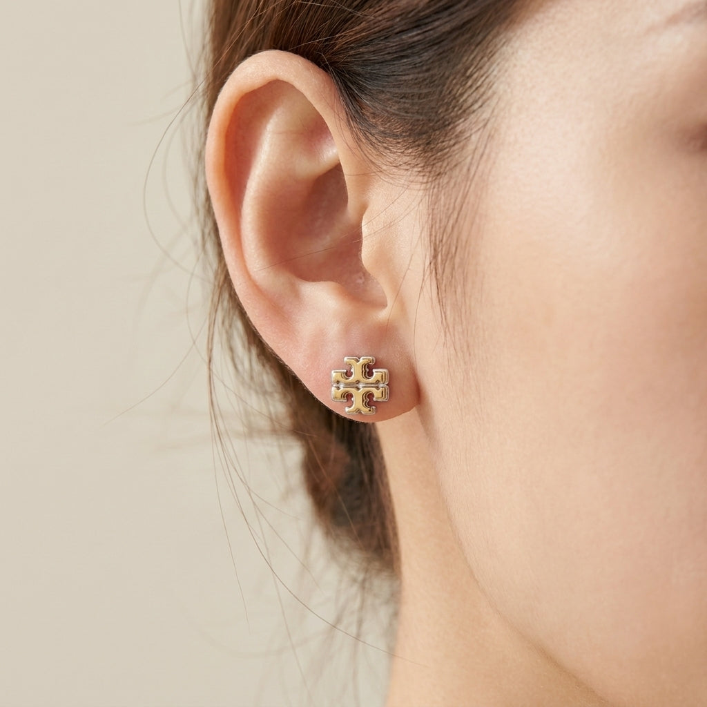 Close-up of a model wearing Tory Burch gold stud earrings, showcasing everyday elegance