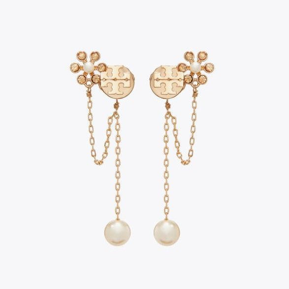 Studio display of Tory Burch gold moondance pearl chain drop earrings featuring double T logo, flower motif, and glass pearl drops.