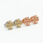 Side angled view of Tory Burch gold stud earrings showing the 3D logo structure and thickness