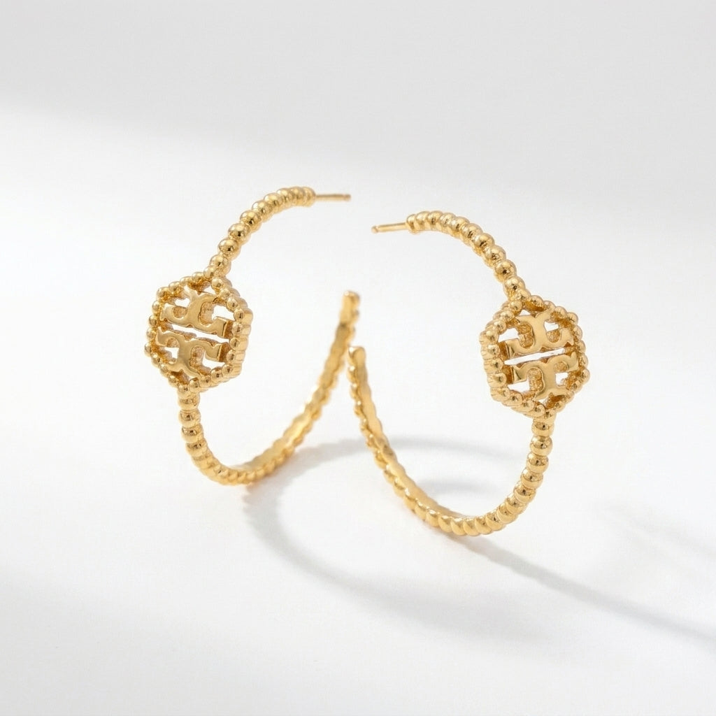 Macro detail of the embossed Double T logo and the vintage-inspired milgrain beading on hex hoops