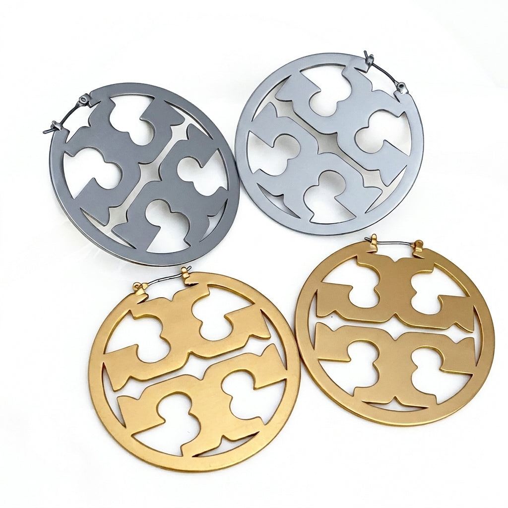 Pair of gold and silver earrings with intricate cut-out designs on a white background