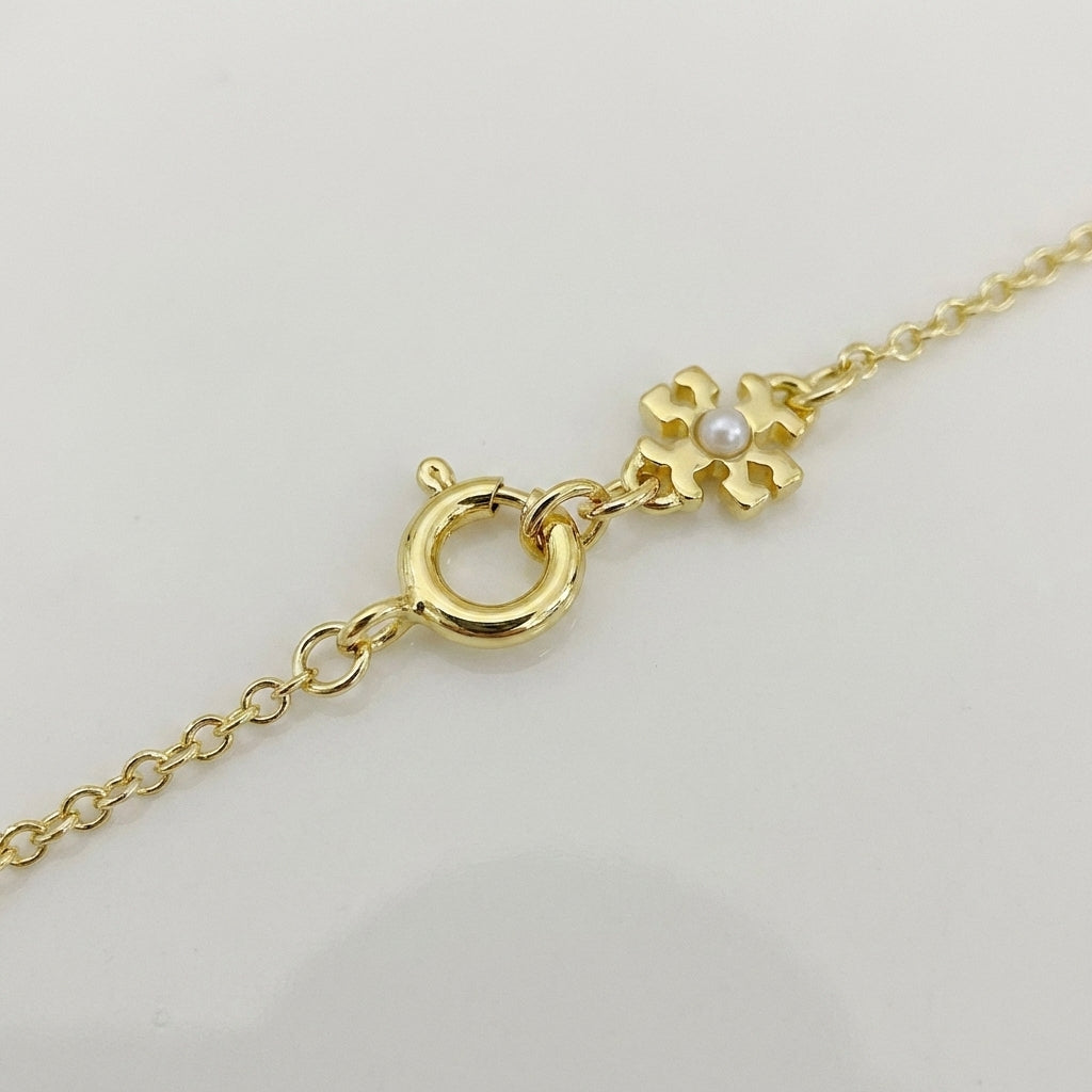 Detail of the lobster clasp and adjustable extender chain on the Tory Burch interlocking necklace with a mini logo charm.