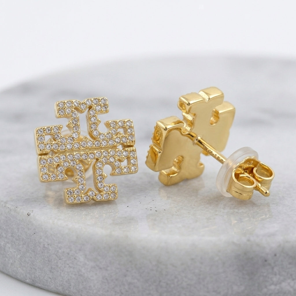 Macro detail of the chevron-patterned crystal setting and hallmark on Tory Burch Kira earrings