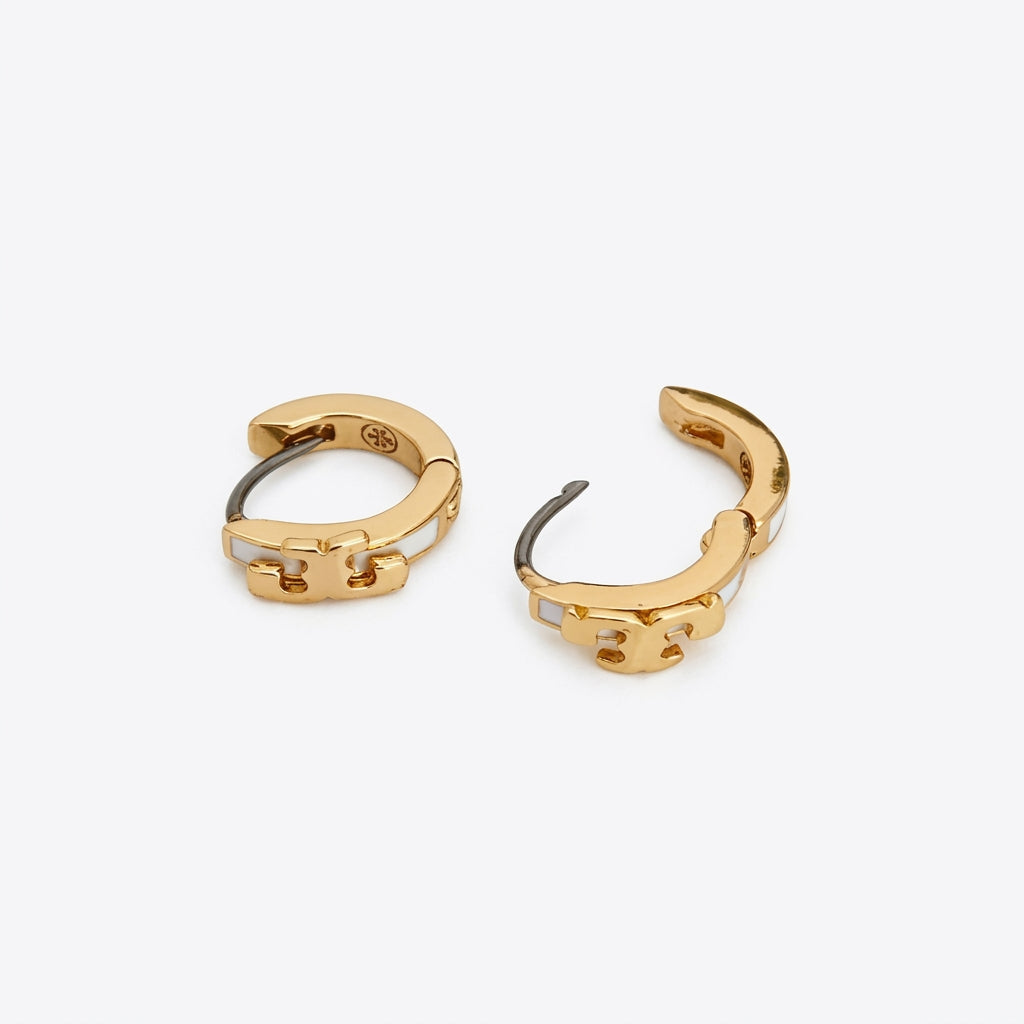 Macro detail of the gold Double T logo and vibrant enamel finish on Kira Huggie Earrings