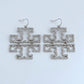 A close-up view of a model wearing the large Tory Burch Double T pave crystal statement earrings in gold to show scale and style.