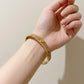 A woman wearing the Tory Burch Miller Enamel Logo Hinge Bracelet, showcasing an effortless luxury style for daily outfit.