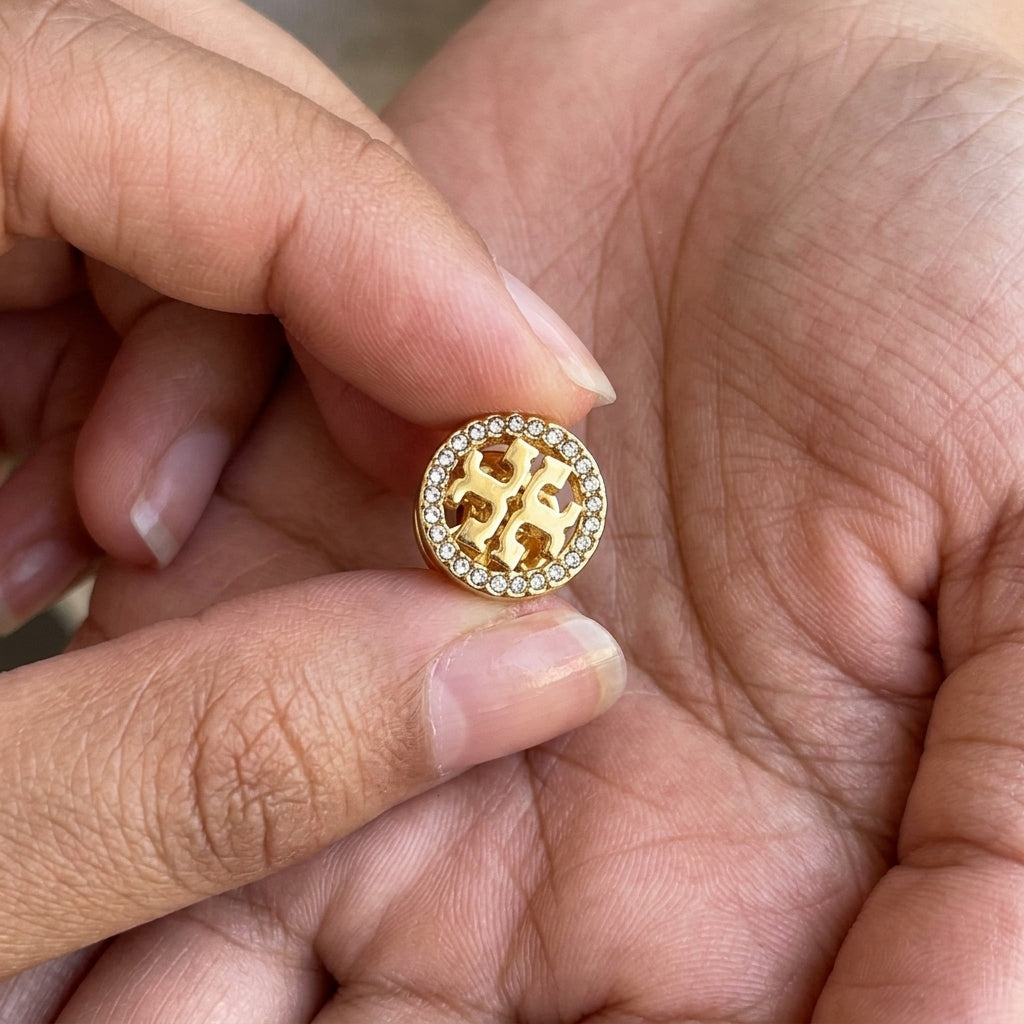 Hand-held size reference of Tory Burch Miller Pave Studs to show actual product scale
