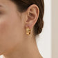 Model wearing Tory Burch Miller Stud Huggie Hoop Earrings to demonstrate the huggie fit and size