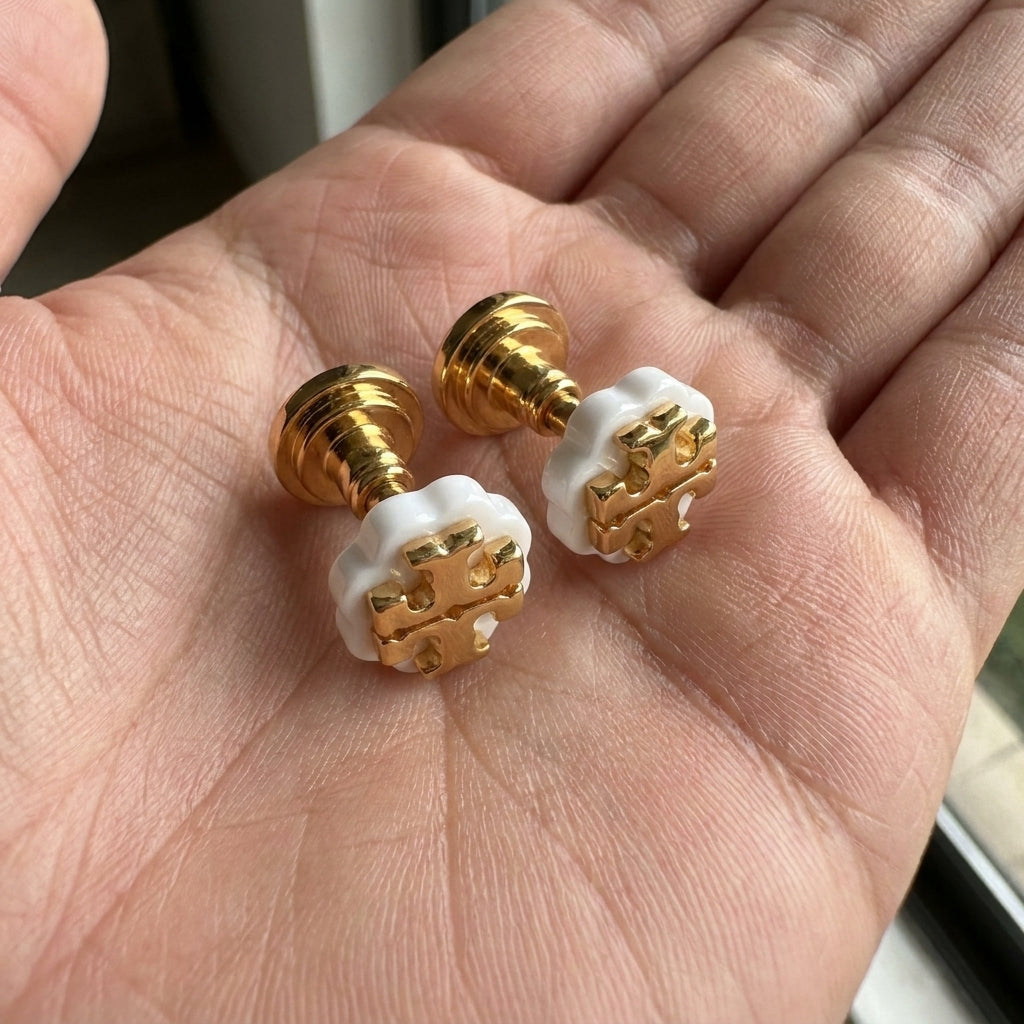 Hand-held size reference of Tory Burch Double Tone Studs to show the delicate daily scale