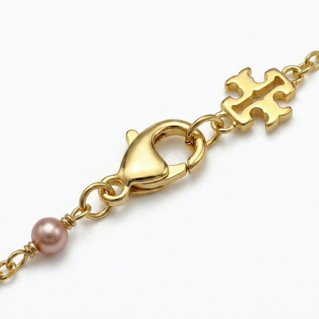 Detailed shot of the lobster clasp and the signature Double T logo tag on the pearl bracelet
