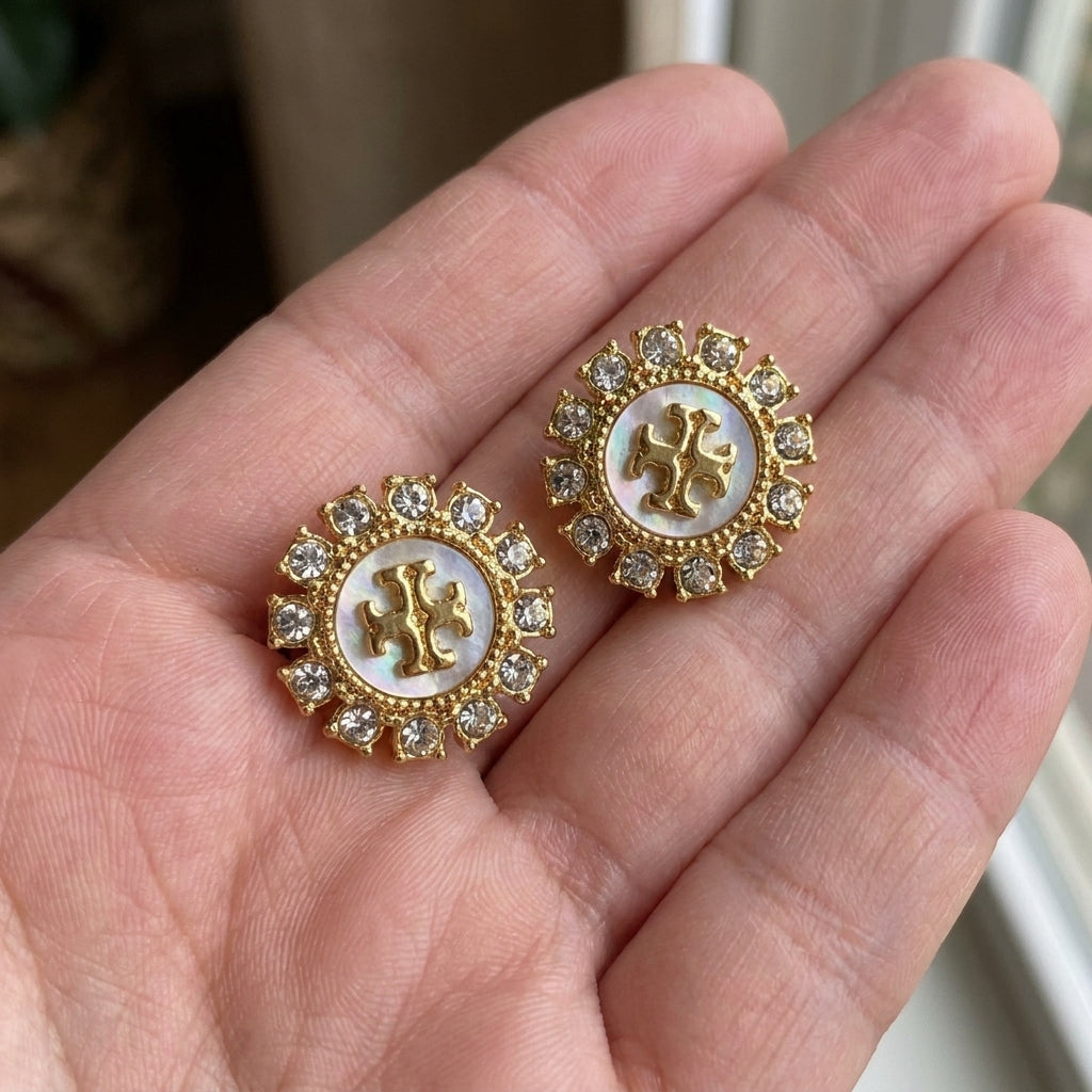 Hand-held view of Tory Burch Moondance Studs to provide a clear scale of the celestial design