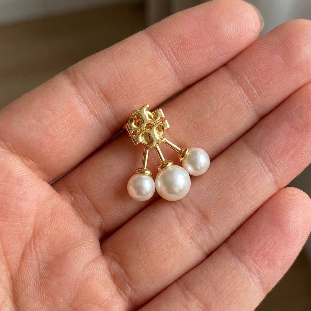 Hand-held size comparison of Tory Burch Front-Back Pearl Earrings showing the scale of the two components