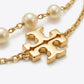 Studio macro close-up view highlighting gold-tone double T logo charm, delicate link chain, and luminous glass pearls.