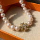 Macro detail of Moondance pearl showing iridescent luster and polished gold bezel logo setting