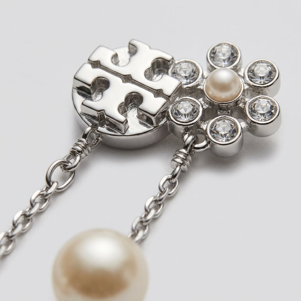 Studio macro profile showing the back of double T logo post, crystalline flower detail, and silver chain pearl drop mechanism.