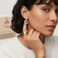 Editorial lookbook profile of a model styling tory burch moondance pearl hoop earrings with a white top.