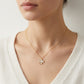 Woman wearing Tory Burch Moondance pendant necklace styled as layered minimalist gold jewelry