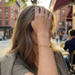 Model adjusts hair wearing Tory Burch Moondance Pearl Bracelet, capturing natural luster in an urban setting