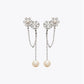 Studio display of Tory Burch silver moondance pearl chain drop earrings with crystalline flower and hanging pearl chain.