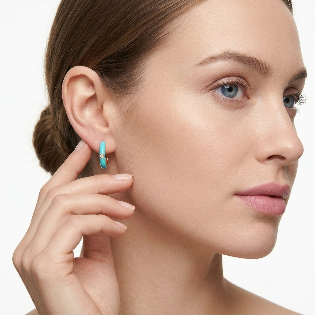 Model wearing vibrant turquoise enamel gold open hoop moissanite earrings in a lifestyle portrait.