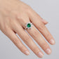 Ring with a green gemstone on a finger against a gray background