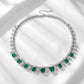 Flatlay view of a vintage cushion-cut emerald fringe statement necklace under soft shadows.