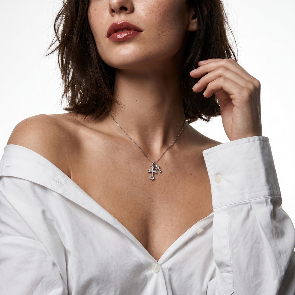 Woman wearing vintage gothic double cross pave pendant necklace on collarbone.