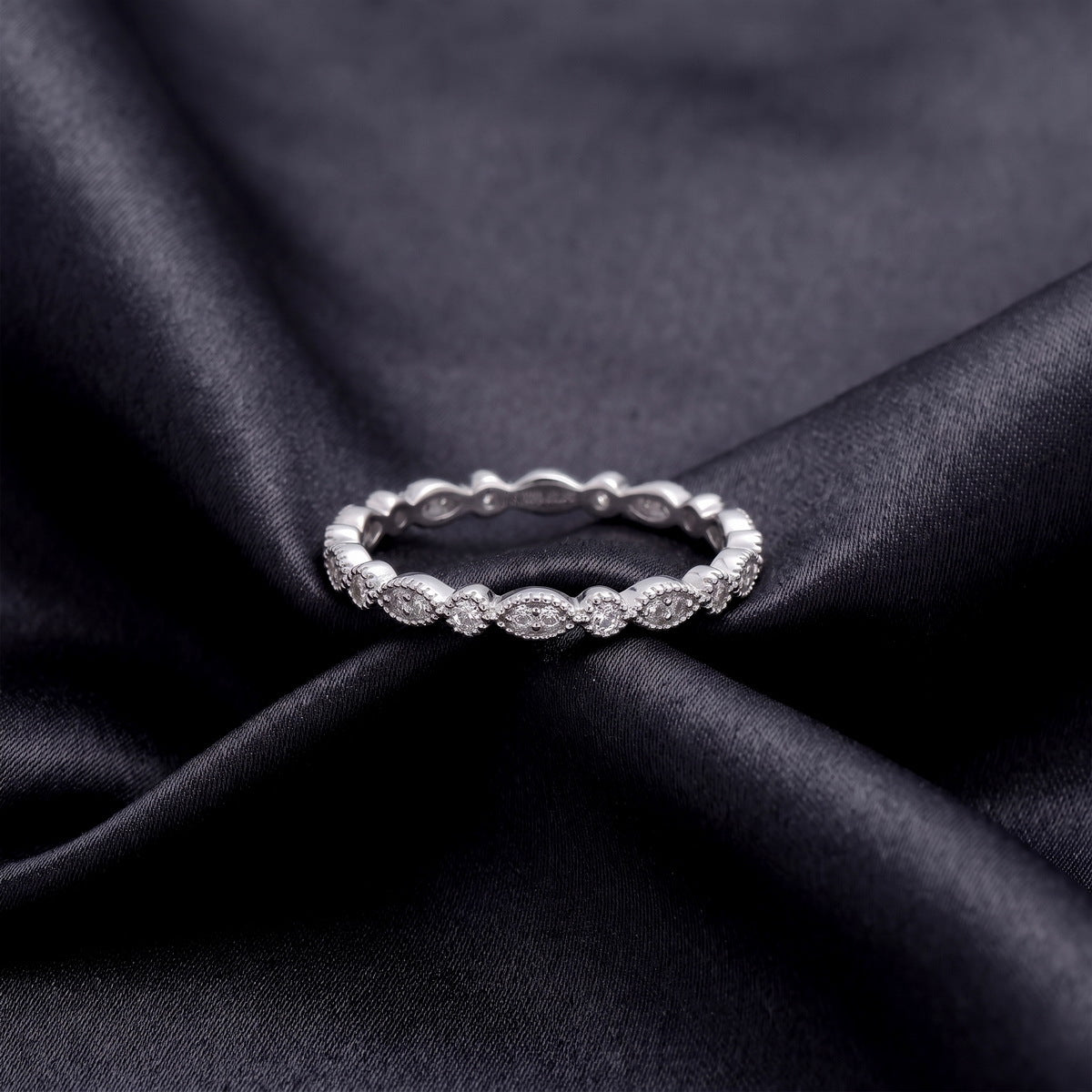 Vintage milgrain marquise and round lab grown diamond wedding band resting flat on dark black silk