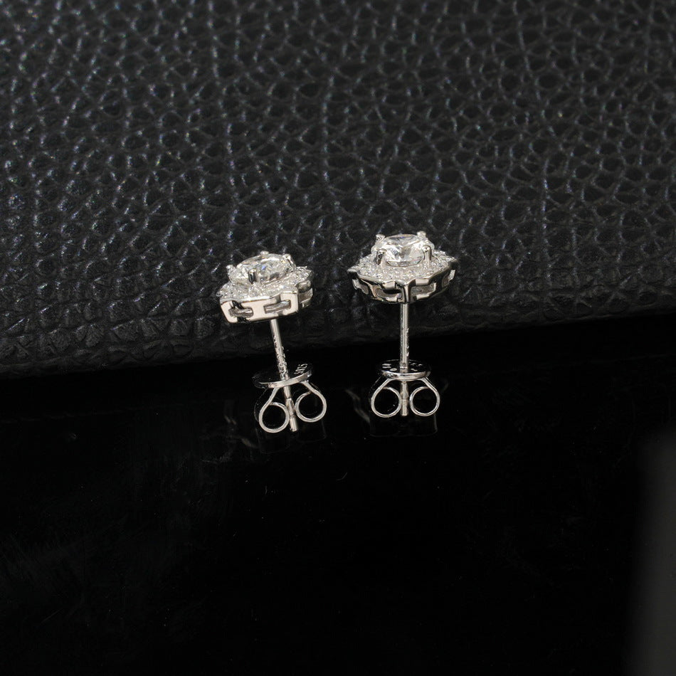 Vertical shot of vintage octagonal scalloped halo lab diamond stud earrings on black leather.