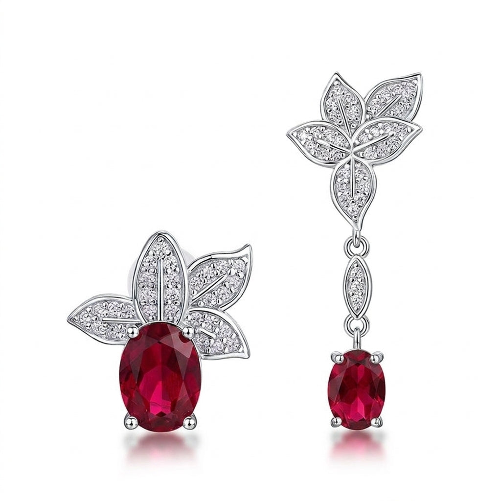 White background front view of a pair of vintage oval ruby asymmetric foliage dangle and stud earrings.
