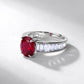 Silver ring with a red gemstone and clear stones on a light gray background