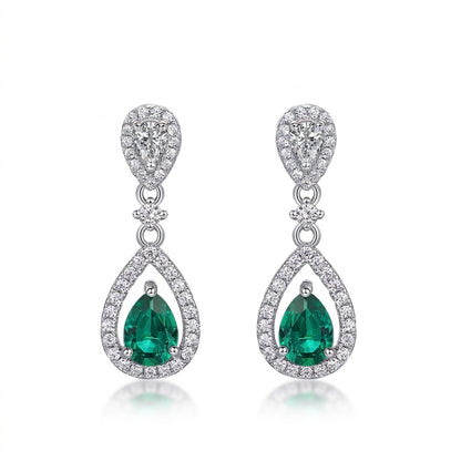 White background front view of a pair of vintage pear-cut emerald hollow halo drop earrings.