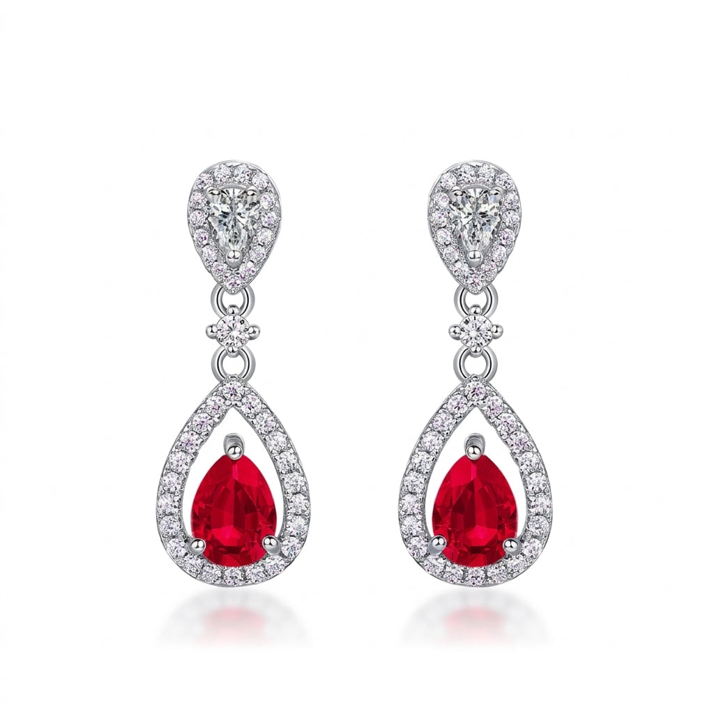 White background front view of a pair of vintage pear-cut ruby hollow halo drop earrings.