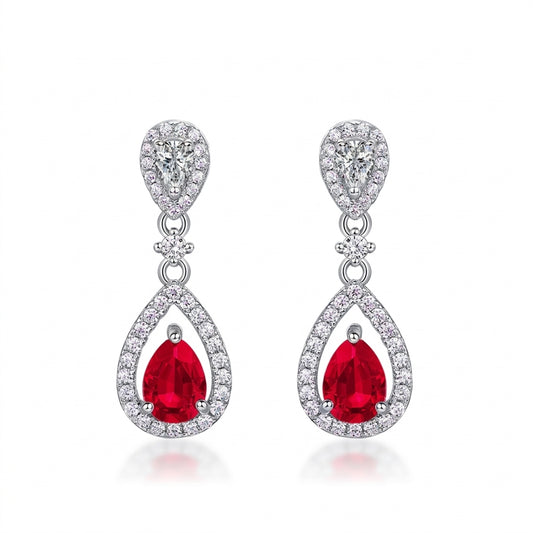 White background front view of a pair of vintage pear-cut ruby hollow halo drop earrings.
