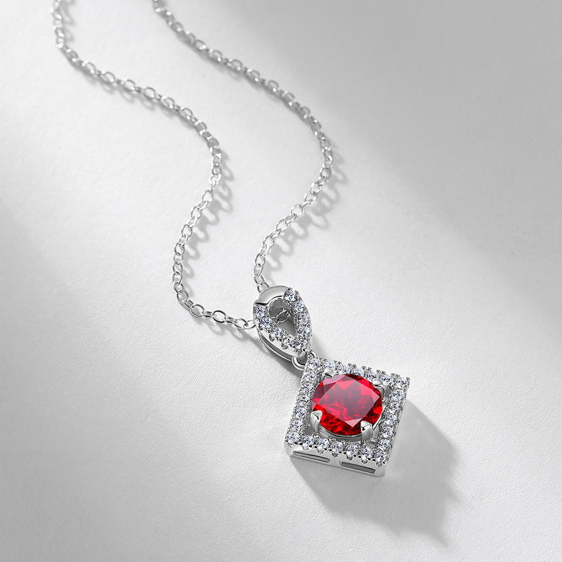 Side angle studio view of a vintage round-cut ruby rhombus pendant necklace casting a soft shadow on a white surface.