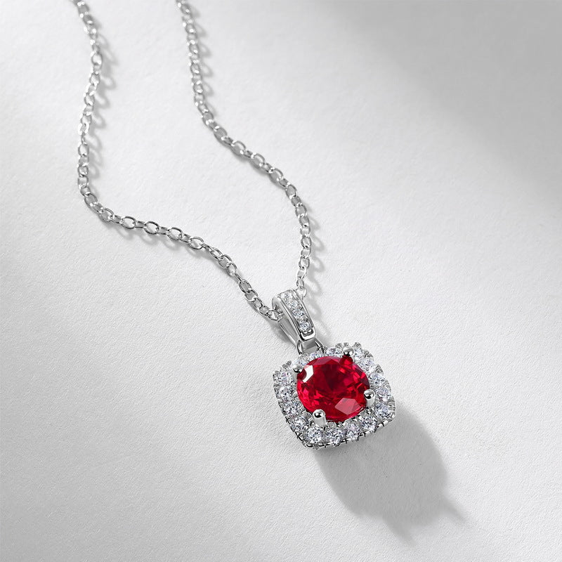 Side angle view of a vintage round ruby cushion halo pendant necklace casting a soft shadow on a white surface.