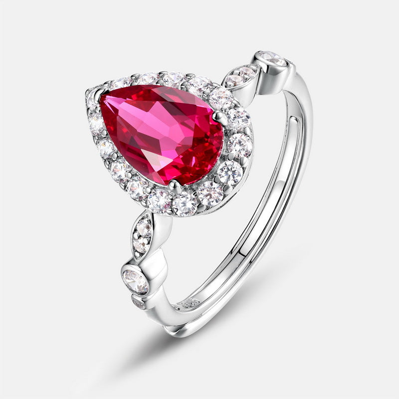 Three-quarter studio product view of a vintage teardrop lab ruby halo ring with an Art Deco marquise-shaped pave shank.