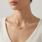 Model wearing the Tory Burch Icon Pave Interlocking Pendant Necklace to demonstrate the drop length and elegant layered look.